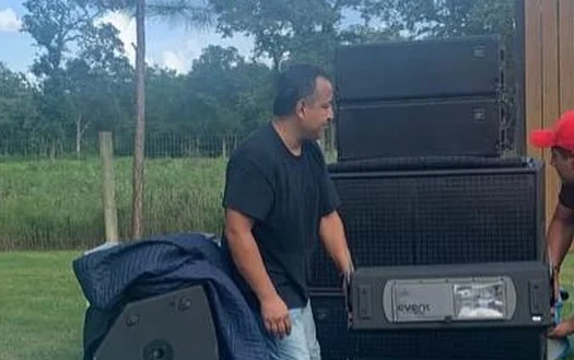 Rodrigo cargando una bocina del equipo del grupo, junto al rack de audio